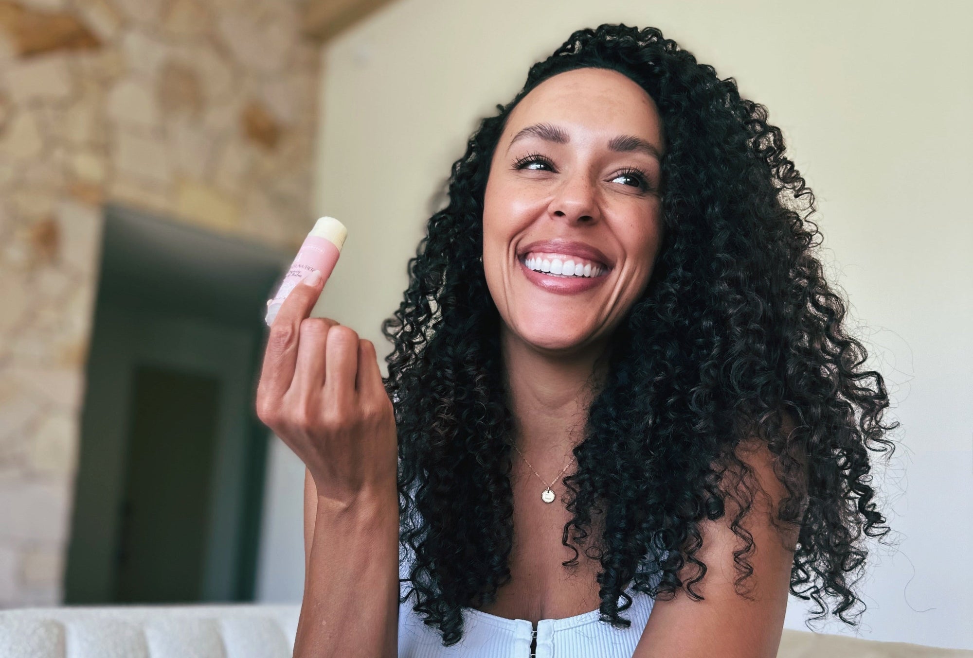 Numbrrrz owner with strawberry organic lip balm sitting on the couch laughing.