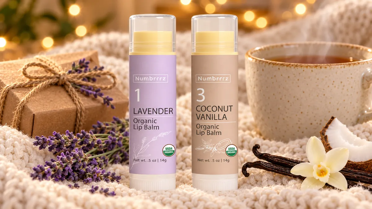 Numbrrrz Lavender and Coconut Vanilla organic lip balm tubes on a cream knit throw with tea, lavender sprigs and a wrapped gift